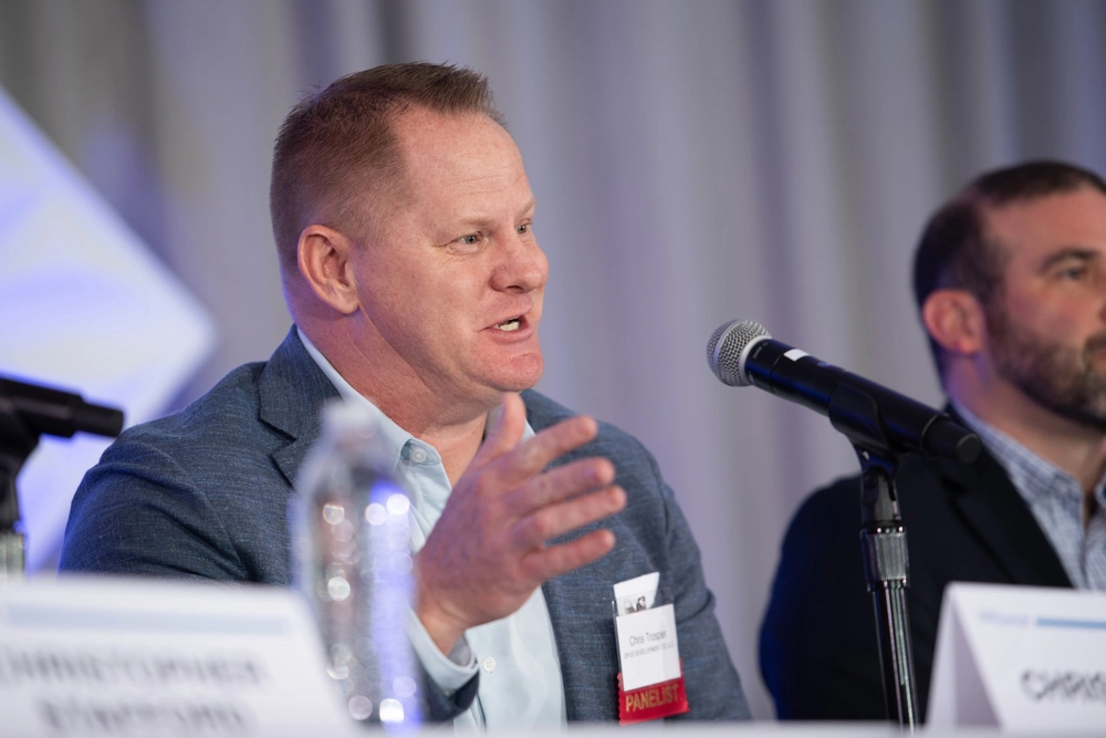 man seated at table speaking into microphone